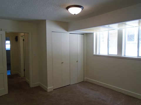 an empty living room with white cabinets and a window